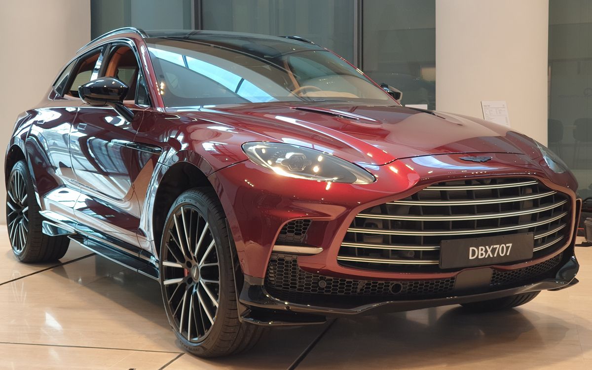 Liquid Crimson Aston Martin DBX707 in a showroom, front three-quarter view