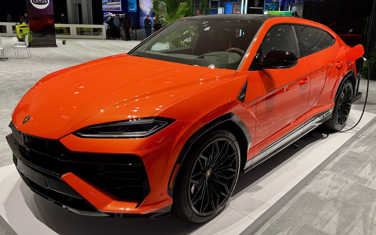 Orange Lamborghini Urus SE on a show stand, front three-quarter view